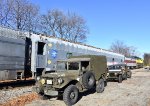 There are a couple of Army colored vehicles resting besides the train along Royal Ave